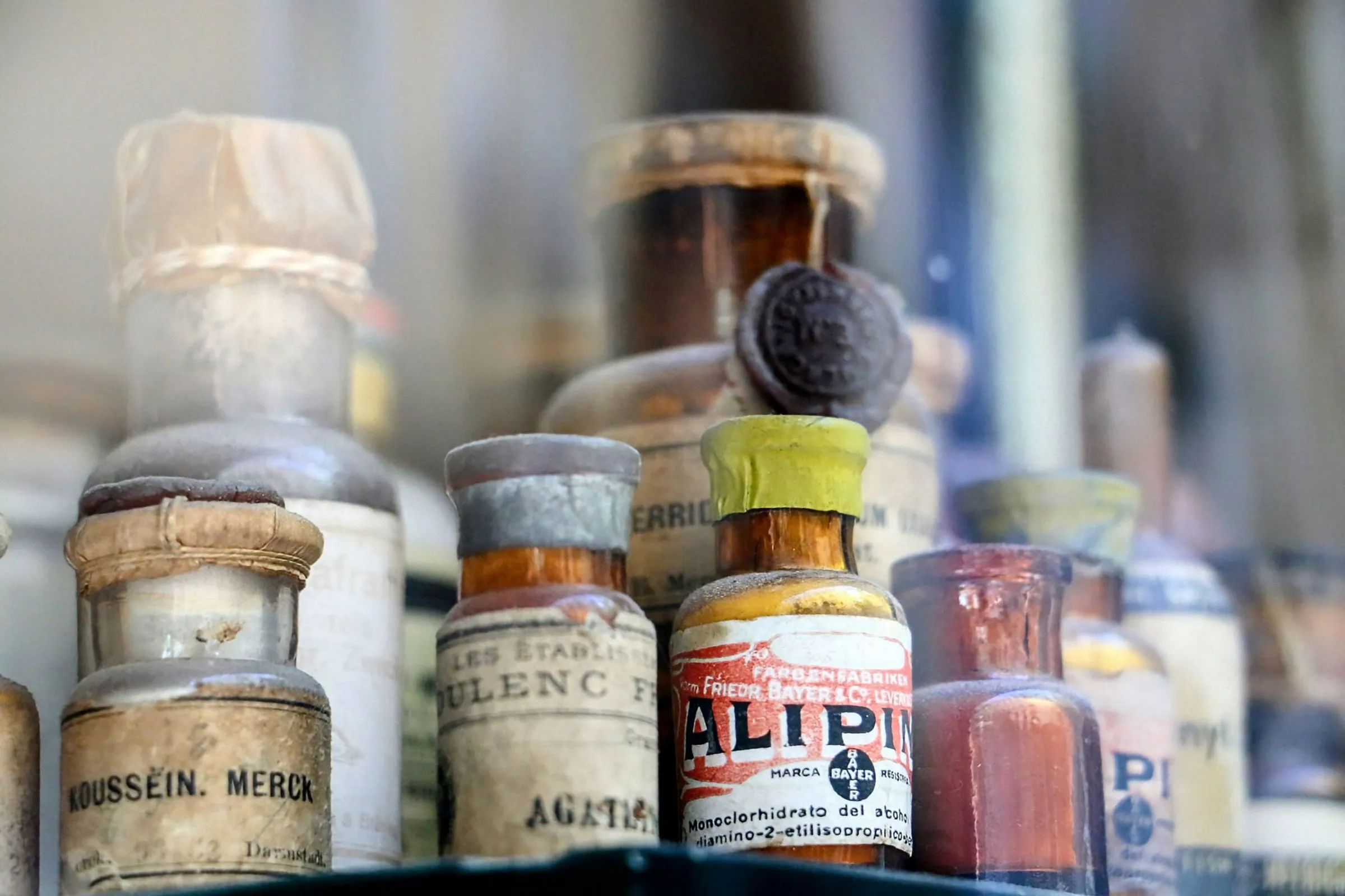 Frascos antiguos de botica con sus etiquetas originales tras el cristal de una vitrina