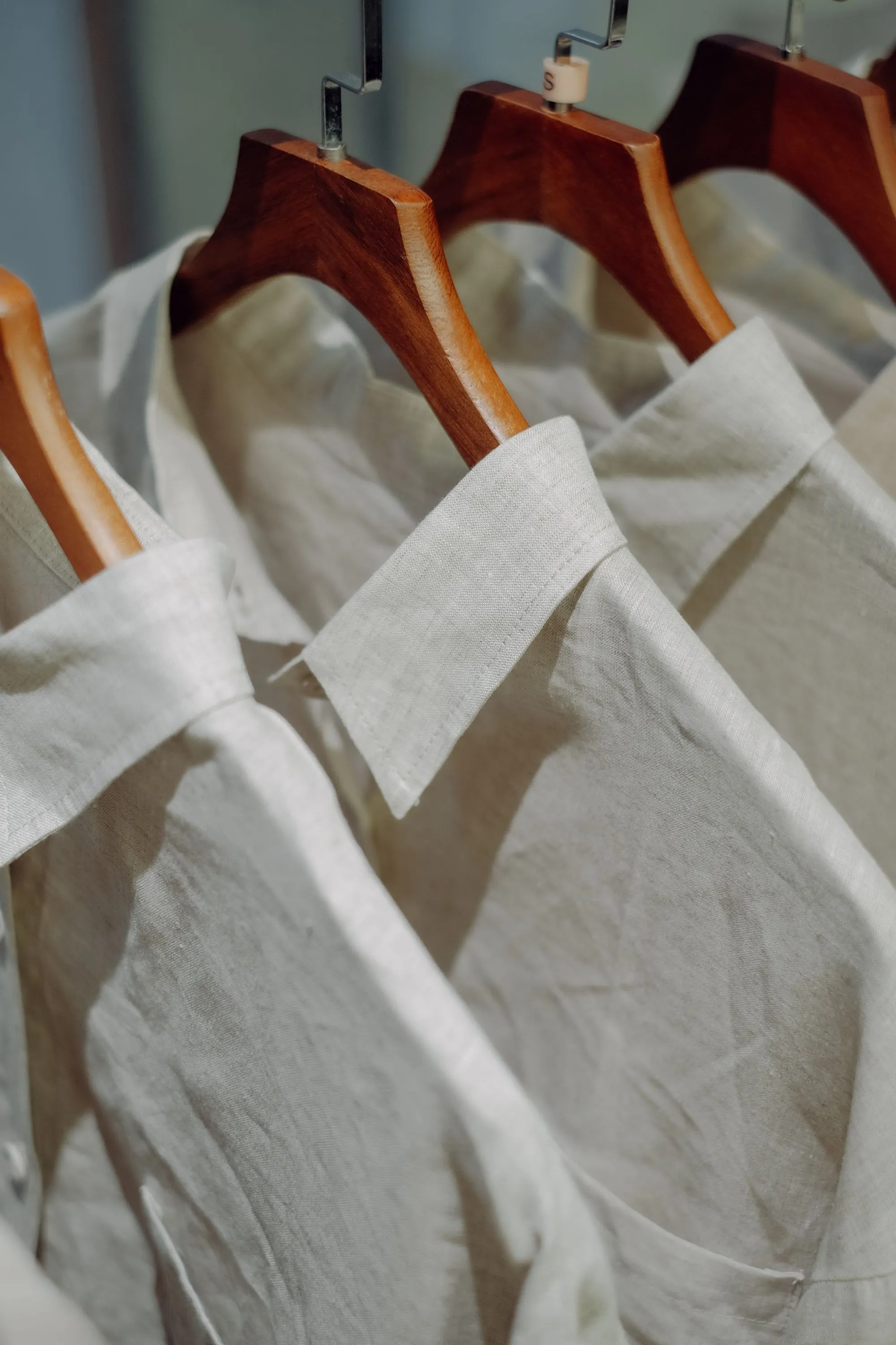 Camisas de lino crudo en perchas de madera, con los cuellos en primer plano