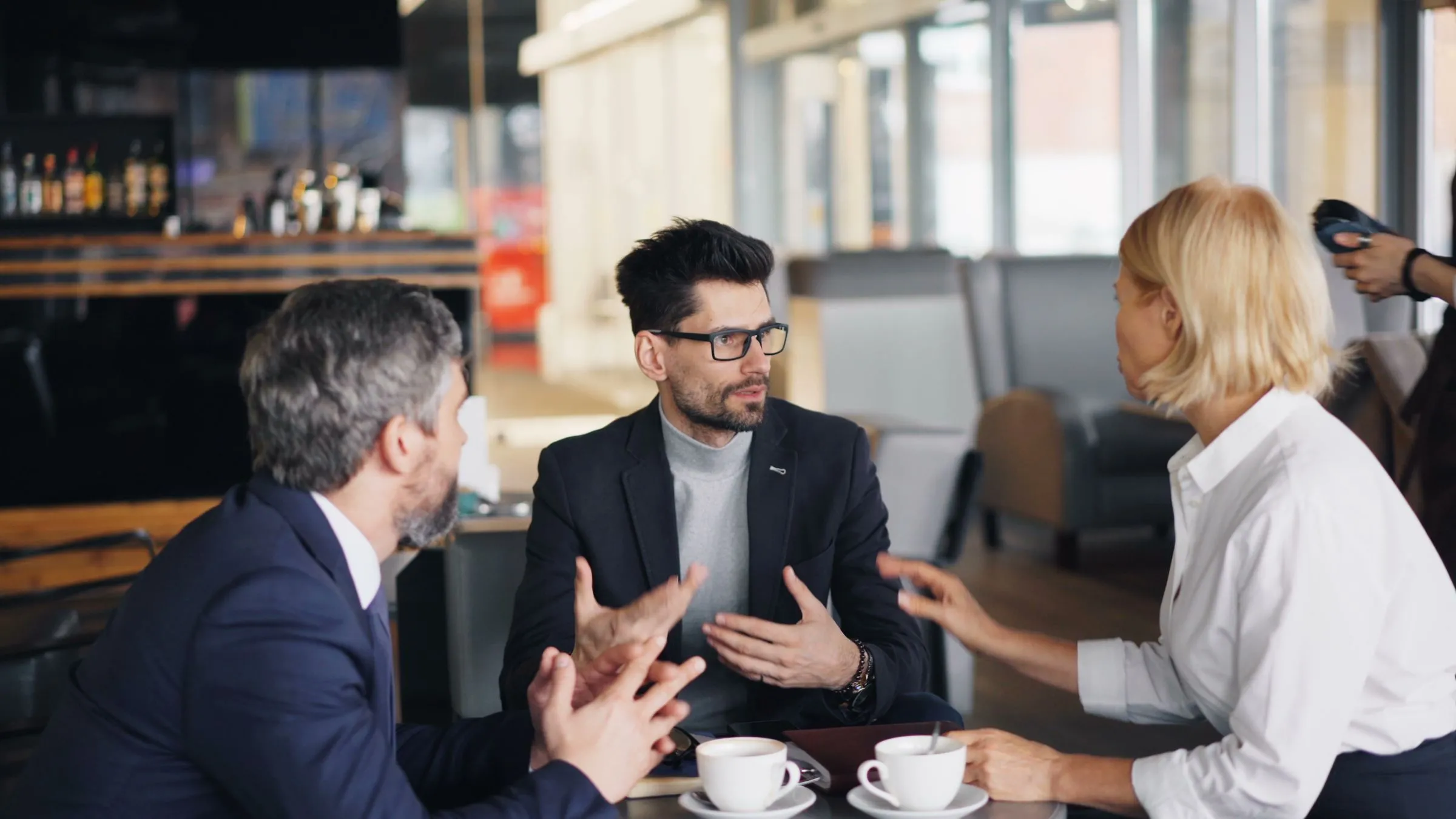 Tres profesionales deliberando alrededor de una mesa con café