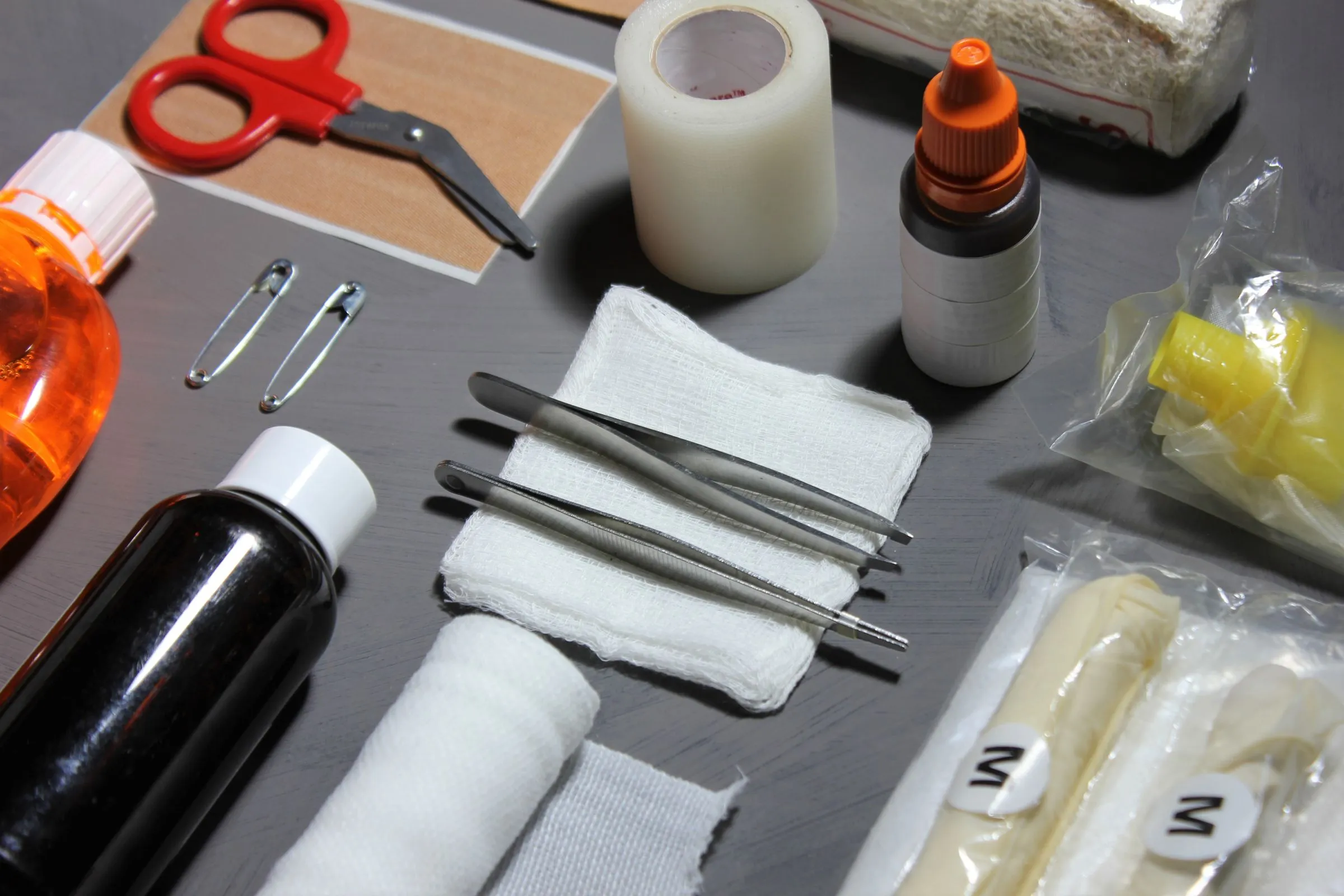 Material de curas ordenado sobre una mesa: tijeras, esparadrapo, gasas, pinzas, imperdibles, vendas y antisépticos