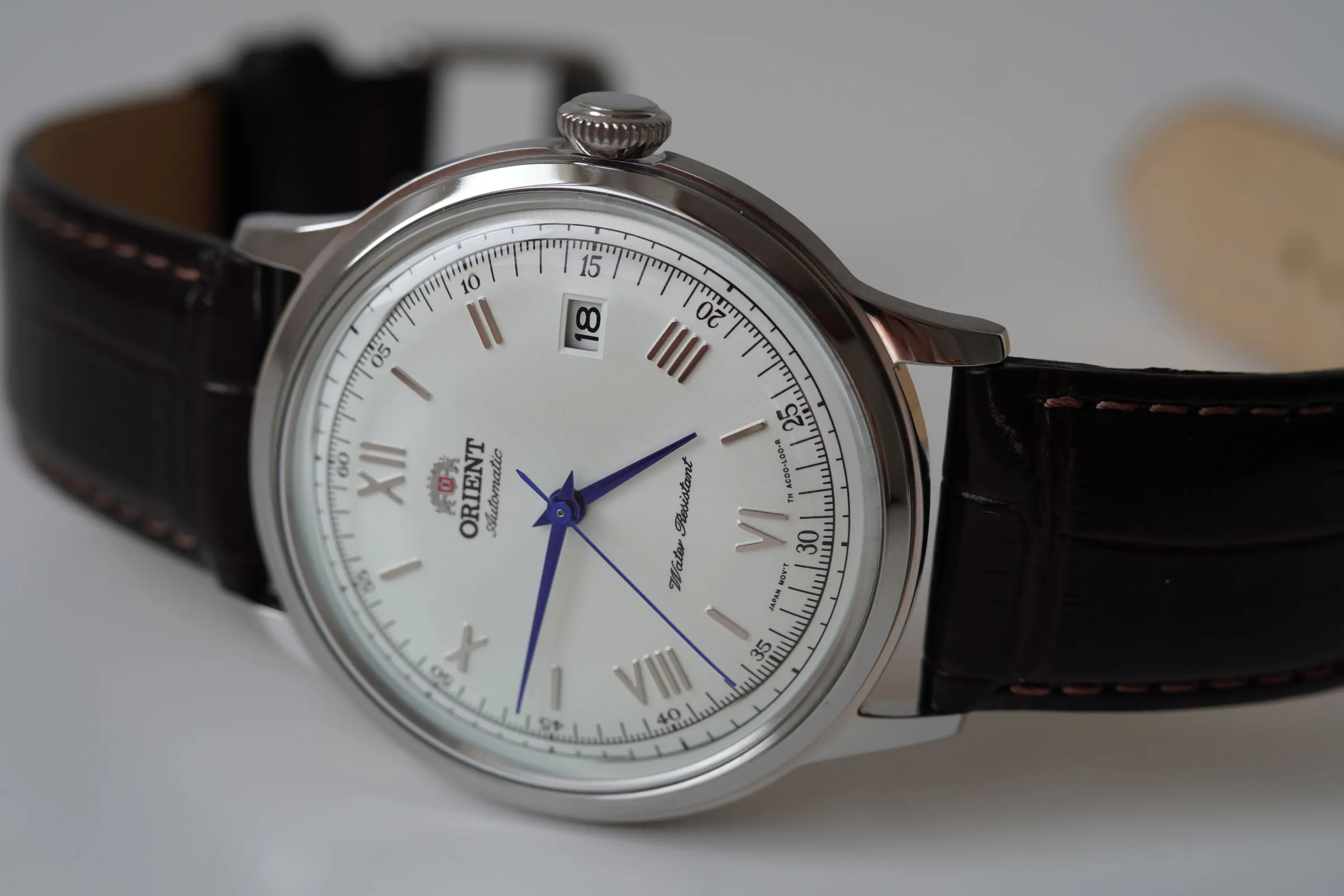 Orient Bambino de esfera blanca con números romanos, agujas azuladas y correa de piel marrón